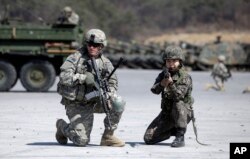 FILE - A U.S. Army soldier and a South Korean Army soldier take their position during joint military exercises between South Korea and the United States in Pocheon, north of Seoul, South Korea, March 25, 2015.