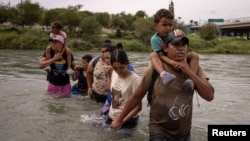 ARCHIVO: Orlando, un migrante de Ecuador, carga a su compatriota Peter, de cuatro años, mientras caminan por el río Grande desde México hasta Eagle Pass, Texas, EE. UU., el 6 de octubre de 2023.