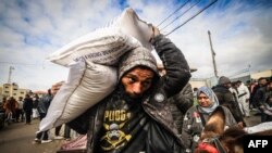 Palestinos desplazados reciben ayuda alimentaria en el centro de la Agencia de las Naciones Unidas para los Refugiados de Palestina (UNRWA) en Rafah, en el sur de la Franja de Gaza, el 28 de enero de 2024.