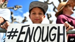 FILE - Zachary Chakin holds a sign as crowds participate in the March for Our Lives rally in support of gun control, March 24, 2018, in San Francisco.