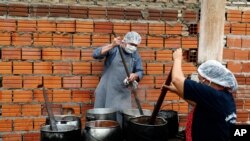 Walter Ferreira, izquierda, y Laura Dure cocinan estofado en un comedor de beneficencia que alimenta a unas 300 personas diariamente en Luque, Paraguay, el lunes 11 de mayo de 2020.