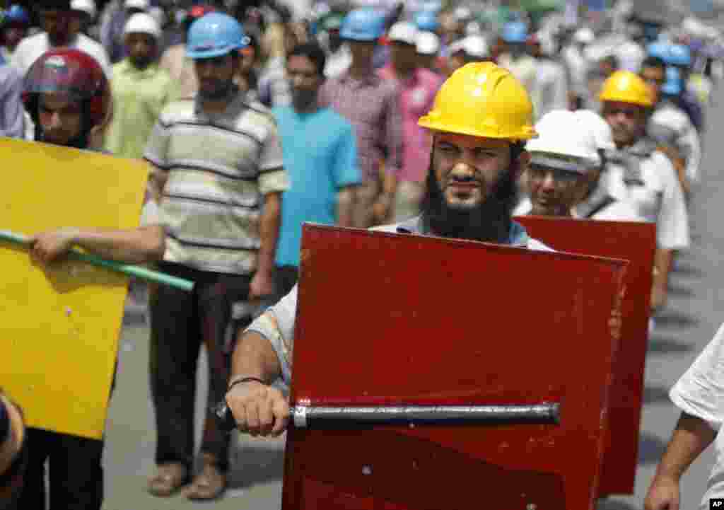 Supporters of Egypt's Islamist President Mohamed Morsi hold sticks and wear protective gear outside of the Rabia el-Adawiya mosque near the presidential palace, in Cairo, Tuesday, July 2, 2013. 
