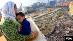 Una madre egipcia sostiene a su hijo en brazos mientras observa a los miles de manifestantes reunidos en la plaza Tahirir demandando la renuncia de Mubarak.