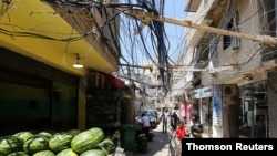 People walk along a street covered with electricity cables at Burj al-Barajneh refugee camp in Beirut