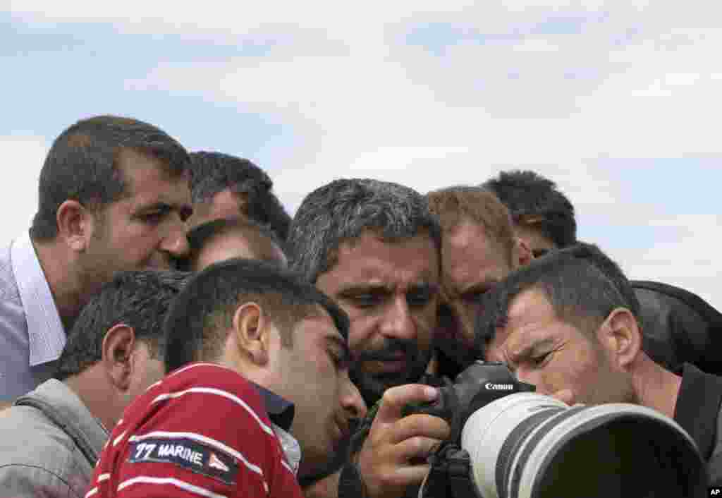 Turkish Kurds watch the fighting between Islamic militants and Kurdish forces to the west of Kobani, Syria, through a photographer's camera at the Turkey-Syria border near Suruc, Turkey, Sept. 30, 2014. 