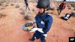 In this photo provided by the Japan Aerospace Exploration Agency (JAXA), a member of JAXA retrieves a capsule dropped by Hayabusa2 in Woomera, southern Australia, Dec. 6, 2020.