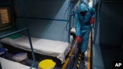 Zdravstveni radnik u zaštitnoj opremi čisti kabinu u vozu koji služi kao improvizovani centar za staranje o zaraženima Kovidom 19 u Indiji (Foto: AP)
