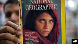 Inam Khan, owner of a book store, shows a copy of a National Geographic magazine featuring a photo of Afghan refugee Sharbat Gulla, now 46 and in police custody in Pakistan, from his collection in Islamabad, Pakistan, Oct. 26, 2016.