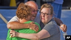 Una familia se abraza desesperada en las afueras del complejo de cines en Aurora, donde buscaban frenéticamente a su hijo de 27 años.