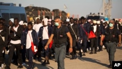 Italian border police officers escort sub Saharan men on their way to a relocation center, after arriving aboard the Golfo Azzurro rescue vessel at the port of Augusta, in Sicily, June 23, 2017. 