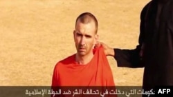 An image taken from a video released by the Islamic State (IS) and identified by private terrorism monitor SITE Intelligence Group on Sep. 2, 2014 purportedly shows footage of a masked militant in a desert landscape threatening to kill British David Cawth