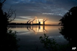 FILE - The coal-fired Plant Scherer, one of the nation's top carbon dioxide emitters, stands in the distance in Juliette, Ga., June, 3, 2017. U.S. President Donald Trump on June 1, 2017, pulled the U.S. from the Paris climate agreement, striking a major blow to worldwide efforts to combat global warming and distancing the country from its closest allies abroad.