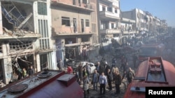 Syrian army soldiers and civilians inspect the site of two bombings in the Syrian city of Homs, in this photo provided by the state-owned Syrian Arab News Agency (SANA), Dec. 28, 2015.
