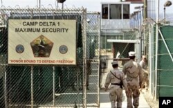 FILE - U.S. military guards walk within Camp Delta military-run prison, at the Guantanamo Bay U.S. Naval Base, Cuba.