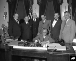 FILE - President Franklin D. Roosevelt signs a bill at the White House, June 16, 1933.