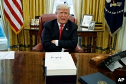 President Donald Trump speaks with reporters after signing the tax bill and continuing resolution to fund the government, in the Oval Office of the White House in Washington..
