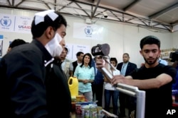 U.S. Ambassador to the United Nations Nikki Haley, background center, looks on as a bandaged Syrian refugee has his iris scanned at a supermarket, May 21, 2017, in Zaatari Refugee Camp, Jordan.