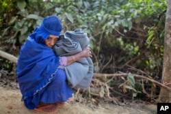 A Rohingya Muslim woman holds on to a blanket and rests on the road after collecting aid at the Kutupalong refugee camp in Ukhiya, Bangladesh, Dec. 21, 2017. Hundreds of thousands of Rohingya people have crossed over from Myanmar into Bangladesh.
