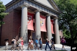 File - A tour group walks through the campus of Harvard University in Cambridge, Massachusetts.
