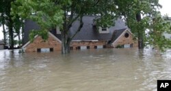 A home is shown as floodwaters from Tropical Storm Harvey rise, Aug. 28, 2017, in Spring, Texas.