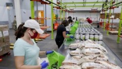 Volunteers load non perishable foods green grocery bag that are then boxed up and put on a pallet for distribution to a school student food program in the area at the Houston Food Bank Wednesday, Oct. 14, 2020, in Houston. (AP Photo/Michael Wyke)