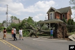Residents walk past a fallen tree following a tornado that struck the night before in Pendleton, Ind., May 28, 2019.