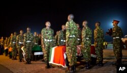Military pallbearers stand to attention next to the coffins of four Kenyan soldiers who were killed in Somalia, at a ceremony to receive their bodies which were airlifted to Wilson Airport in Nairobi, Kenya Monday, Jan. 18, 2016.