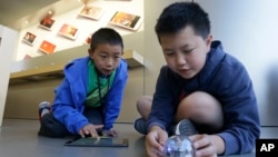 Apple Camp students Brandon Wong, 9, left, and Matthew Choy, 12, learn to program robots using the Sphero SPRK+ with the Lightning Lab application during a Coding Games and Programming Robots session in San Francisco, Wednesday, July 27, 2016. (AP Photo/J