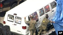 This frame grab from video provided by WPLG-TV shows FBI agents covering a van after the tarp fell off as it was transported from Plantation, Fla., on Friday, Oct. 26, 2018