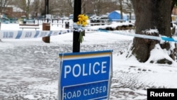 Flowers are left at the cordon near the tent covering the park bench where former Russian intelligence officer Sergei Skripal and his daughter Yulia were found poisoned in Salisbury, Britain, March 19, 2018.