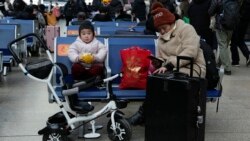 A child eats bread while waiting for a train at the South Train Station in Beijing, China on January 14, 2022. (AP Photo/Ng Han Guan)