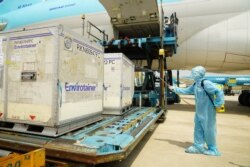 A health official sprays disinfectant on the first batch of AstraZeneca/Oxford Covid-19 coronavirus vaccine shipment after its arrival at the Tan Son Nhat airport in Ho Chi Minh city on February 24, 2021. (Photo by Phu Nguyen / AFP)