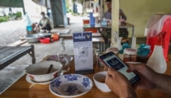 រូបឯកសារ៖ ពលរដ្ឋប្រើប្រាស់​សេវា​ឌីជីថល​របស់​ធនាគារ​ដើម្បីទូទាត់​ប្រាក់​បរិភោគ​អាហារ​នៅ​តូប​អាហារ​តូចៗ​តាម​ដងផ្លូវ នៅ​ខេត្ត​បាត់ដំបង នៅ​ថ្ងៃទី២៥ ខែកញ្ញា ឆ្នាំ២០២១។ (ខាន់ សុគុំមនោ/វីអូអេ)