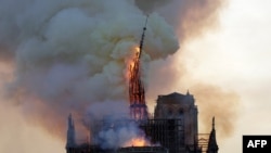 The steeple and spire of the landmark Notre-Dame Cathedral collapses as the cathedral is engulfed in flames in central Paris on April 15, 2019.