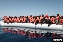 FILE - A plastic raft overcrowded with migrants drifts in the central Mediterranean Sea, May 18, 2017.