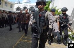 Jakarta Governor Basuki Tjahaja Purnama, popularly known as "Ahok," center, is escorted by anti-terror policemen as he leaves North Jakarta District Court in Jakarta, Indonesia Tuesday, Dec. 20, 2016.