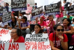Protesters shout slogans while displaying placards denouncing China during a rally outside of the Chinese Consulate hours before the Hague-based UN international arbitration tribunal is to announce its ruling on South China Sea, July 12, 2016, in the Phi