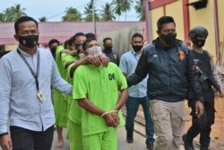 Polisi mengawal seorang terduga pemburu gajah dan pembeli gading untuk presentasi pada konferensi pers di markas polisi di Aceh Timur, Kamis, 19 Agustus 2021. (AP/Riska Munawarah)