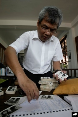 Director of Documentation Center of Cambodia, Youk Chhang selects photos among about a thousand of newly-discovered photo collection of detainees at the former Khmer Rouge main prison S-21, in his office in Phnom Penh, Cambodia, Monday, Aug. 20, 2012. Pho