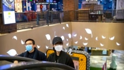 Una pareja usa máscaras faciales mientras suben por una escalera mecánica en un centro comercial en Beijing, el sábado 7 de marzo de 2020.