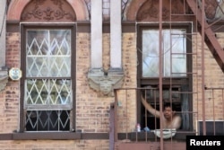 Seorang pria melongok dari apartemennya di tengah gelombang panas yang melanda New York, AS, 21 Juli 2019. (Foto: Reuters)