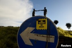 FILE - A "No Border, No Brexit" sticker is seen on a road sign in front of the Peace statue entitled "Hands Across the Divide" in Londonderry, Northern Ireland, Jan. 22, 2019.