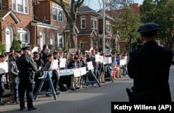 FILE - Police stand guard as students from Rambam Mesivta Orthodox Jewish high school protest across the street from the home of a former Nazi prison camp guard, in New York, Nov. 9, 2017.