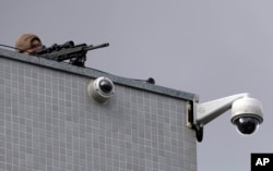 Un francotirador de la policía federal apunta con su arma mientras manifestantes protestan contra el ex presidente de Brasil, Luiz Inácio Lula da Silva, frente al Departamento de Policía Federal en Curitiba, Brasil, el viernes 6 de abril de 2018.