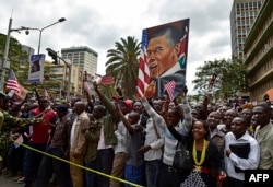 Crowds of Kenyans cheer and hold a painting representing US President Barack Obama near Memorial Park, in Nairobi on July 25, 2015.