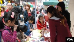 有家長帶同年幼子女參觀中國維權律師關注組的攤位，了解中國維權律師子女被當局剝奪人權的狀況 (美國之音湯惠芸)