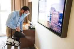 In this Monday, July 6, 2020 photograph, an employee wearing a mask due to the coronavirus pandemic fogs disinfectant in a hotel room at the Rove City Centre Hotel in Dubai, United Arab Emirates. Dubai reopened for tourists Tuesday, July 7, 2020.