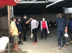 សន្តិសុខកម្មកររោងចក្រកាត់ដេរប្រភឹសឹស ខេមបូឌា ហ្គាមេន អិលធីឌី ក្នុងខេត្តកណ្តាល ត្រួតពិនិត្យកម្តៅកម្មករនៅពេលចូលរោងចក្រ នាថ្ងៃទី២០ ខែមីនា ឆ្នាំ២០២០។ (កាន់ វិច្ឆិកា/VOA Khmer)