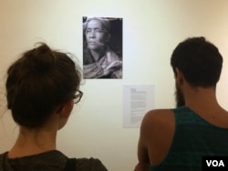 Visitors take a closer look at another fortune teller, Seim Chantha, holding three smoked cigarettes in his hand.