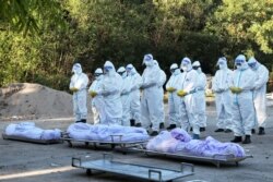 Volunteers pray in front of bodies of people who died due to the coronavirus disease (COVID-19), during their funeral at a cemetery in Mandalay, Myanmar July 14, 2021.
